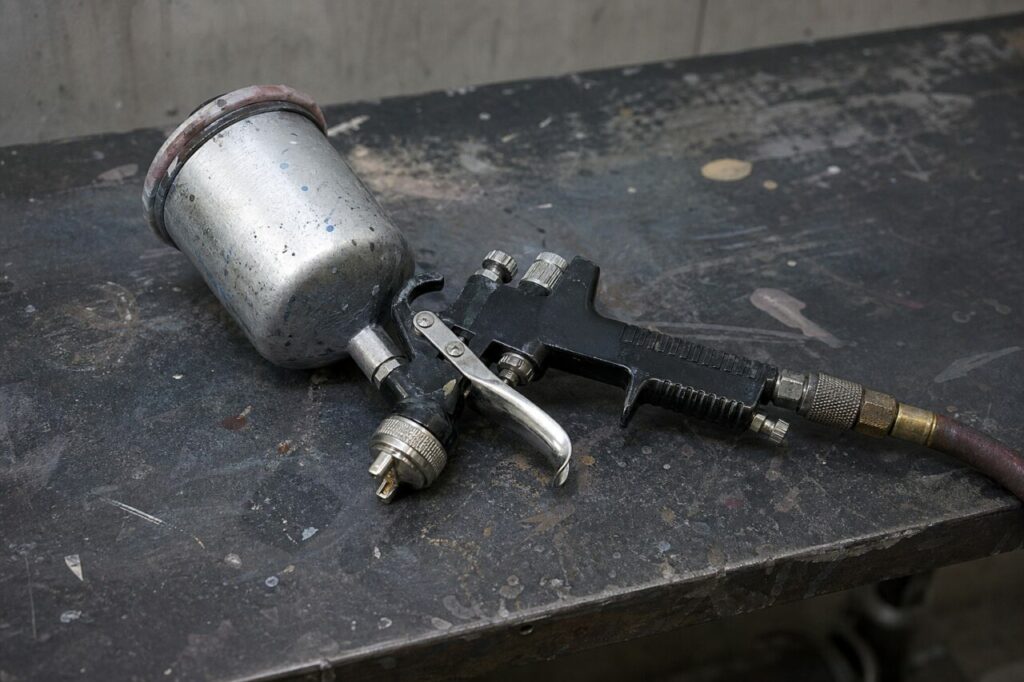 Cup spray gun resting on a workshop bench