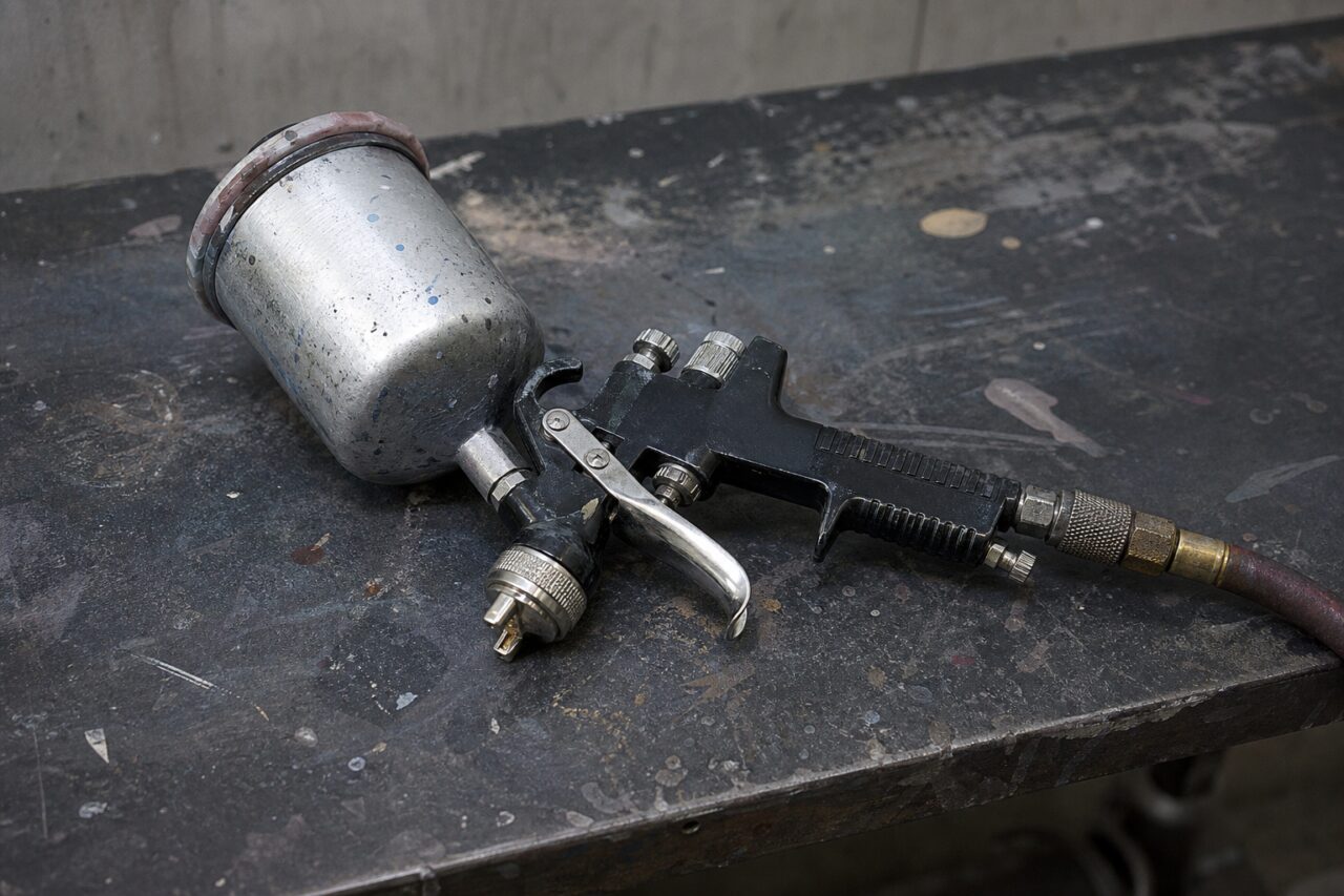 Pistolet de pulvérisation à godet posé sur un établi d’atelier