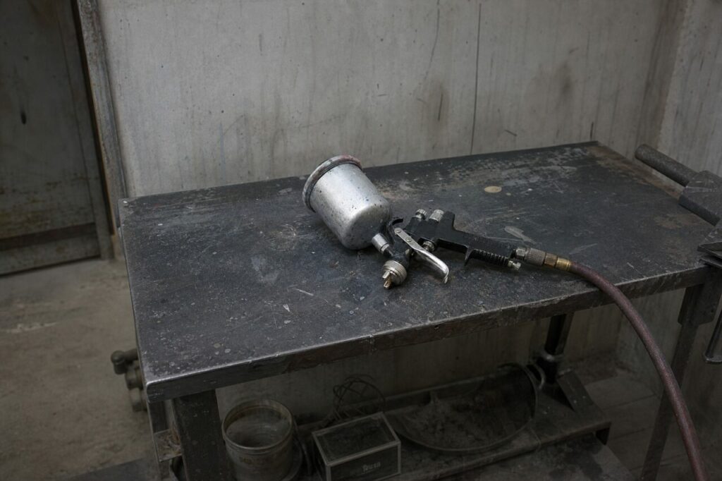 Spray gun on a metal table inside a workshop