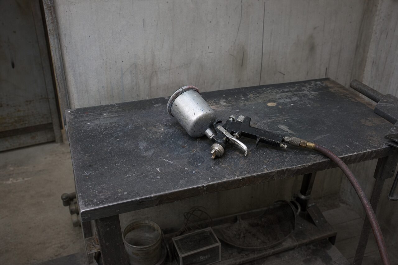 Pistola de pulverização sobre uma mesa metálica numa oficina