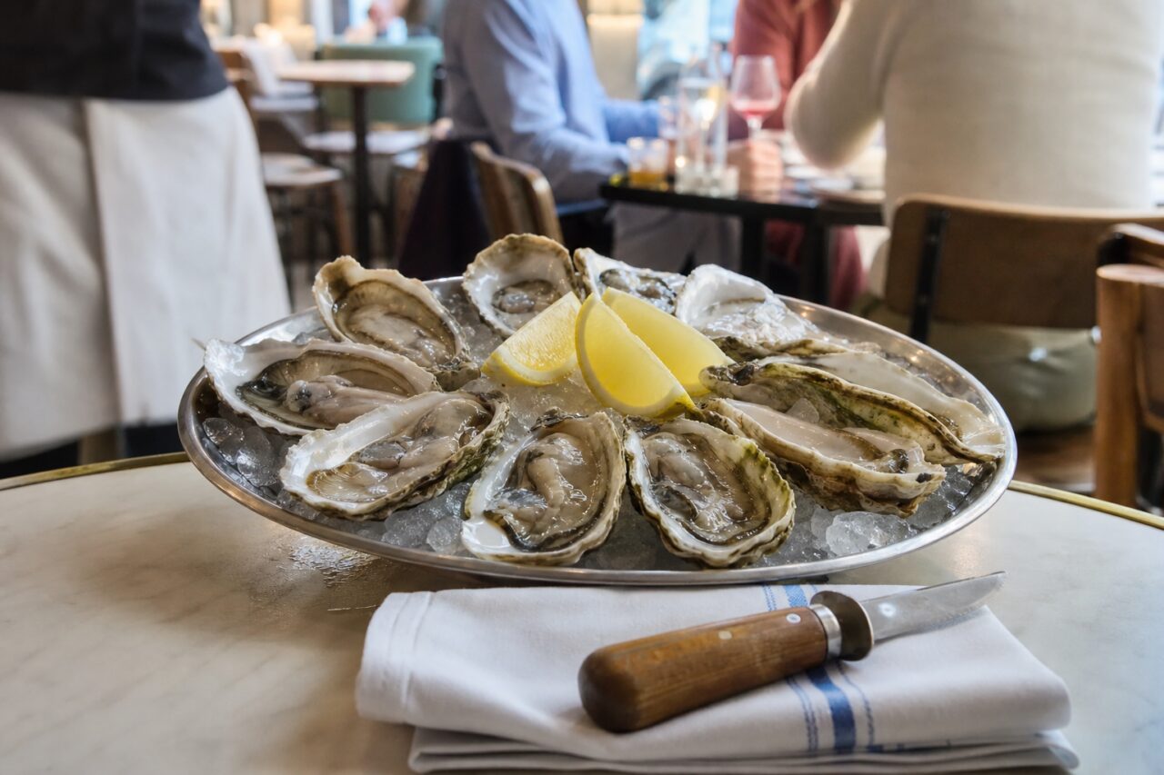 Oyster platter and white wine on a brasserie table