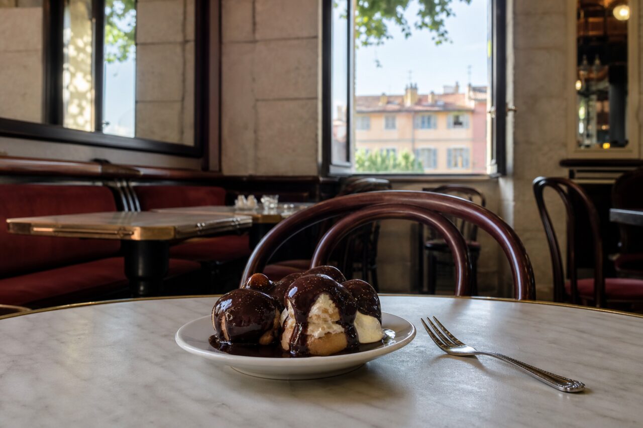Profiteroles de chocolate num prato pequeno com garfo numa brasserie
