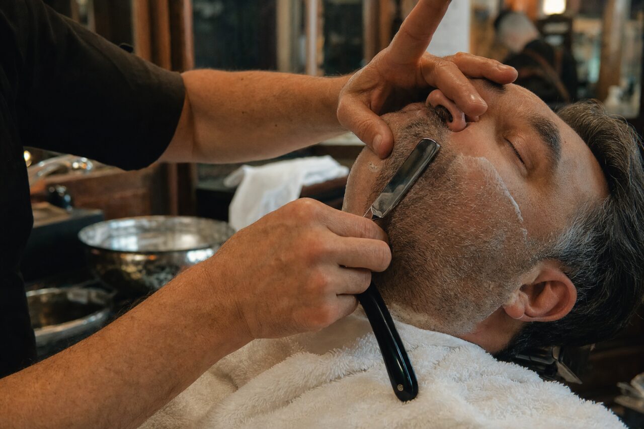Baard scheren met een open scheermes in een kappersstoel