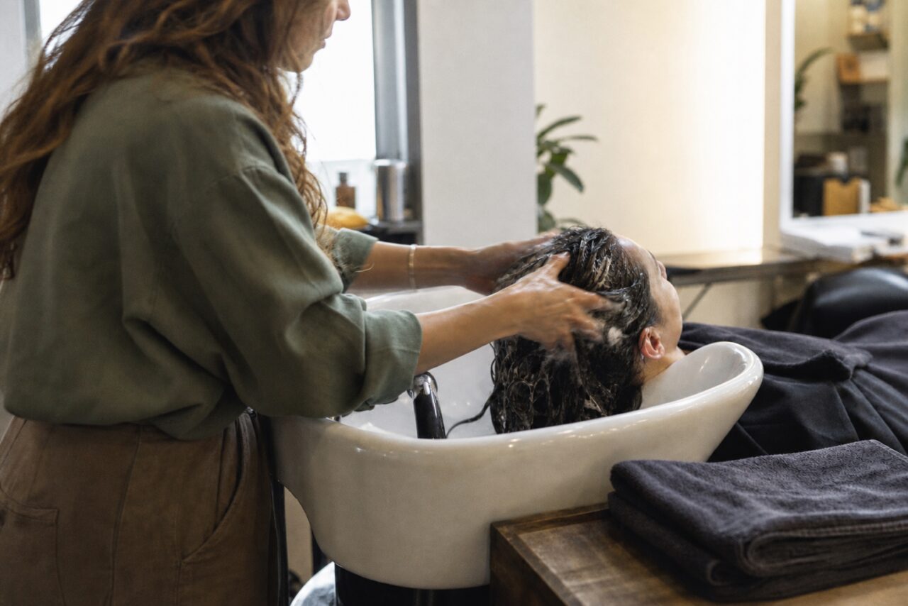 Miroir du salon avec lavage des cheveux, bac blanc et cape noire