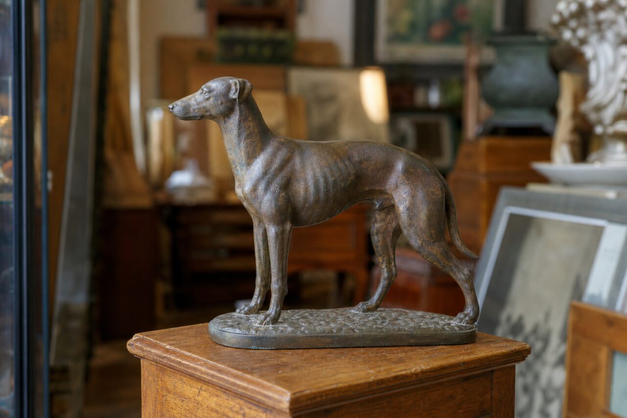 Bronzen hondensculptuur op een houten kast in een brocantewinkel