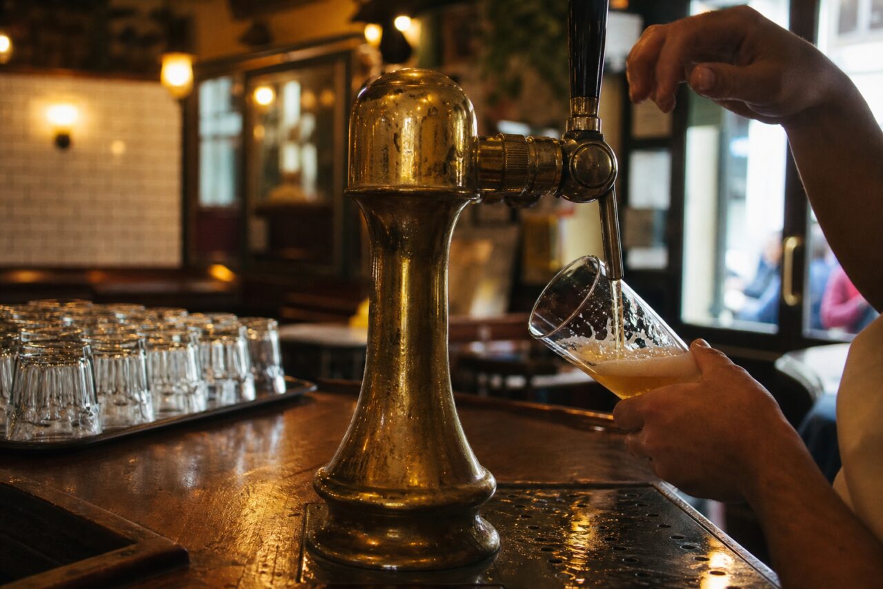 Serving beer at the counter with a brass tap and visible hands