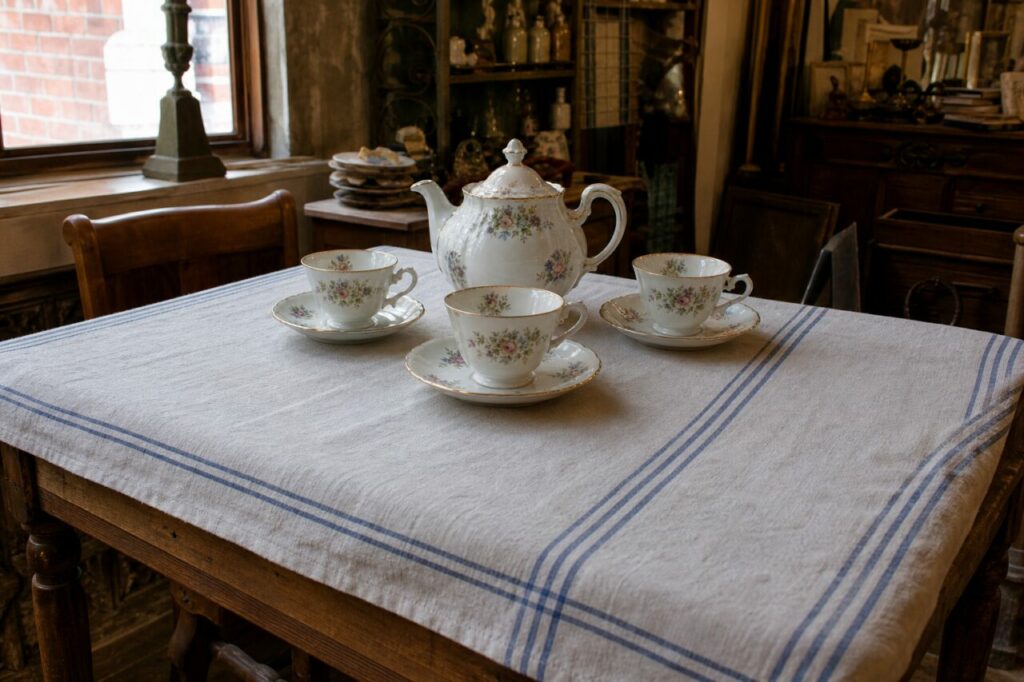 Floral porcelain tea set arranged on a large table in an old shop interior