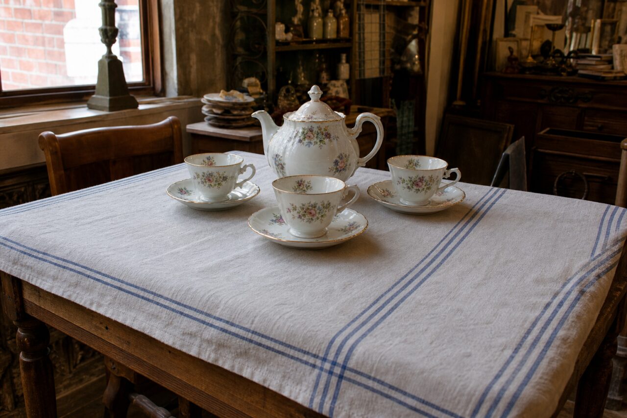 Juego de té floral de porcelana dispuesto sobre una mesa amplia de tienda antigua
