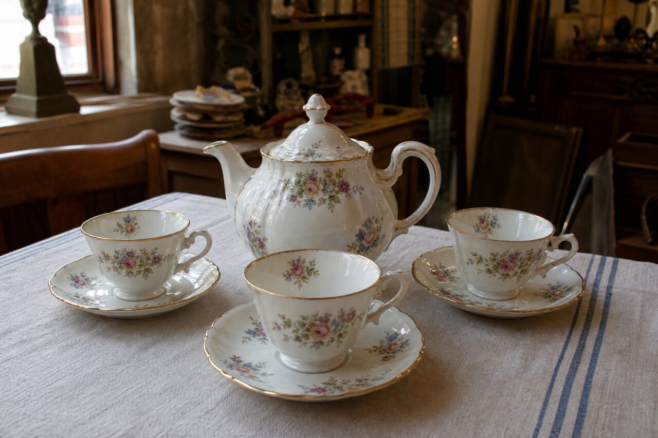 Servizio da tè in porcellana bianca con fiori e bordi dorati in un negozio d’epoca