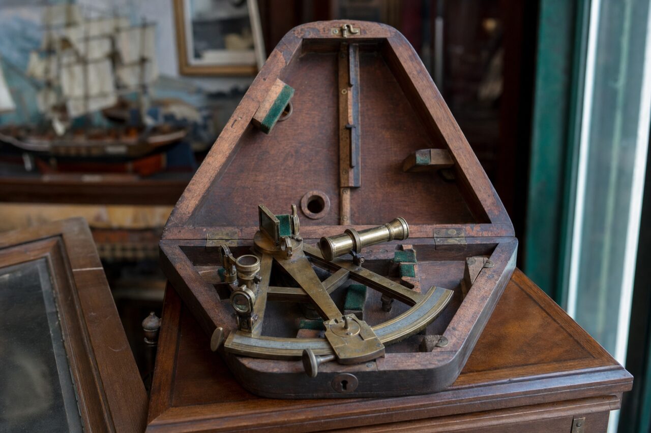 Oude messingkleurige sextant in een geopende houten kist