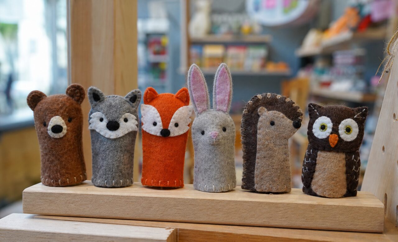 Sechs genähte Tierfiguren aus Textil auf einem Holzsockel
