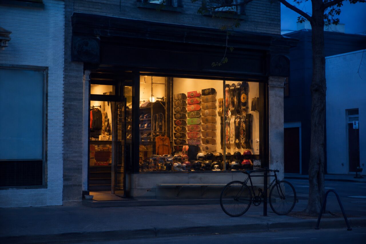 Verlichte skateshopetalage met helmen en kleurige boards in de schemering