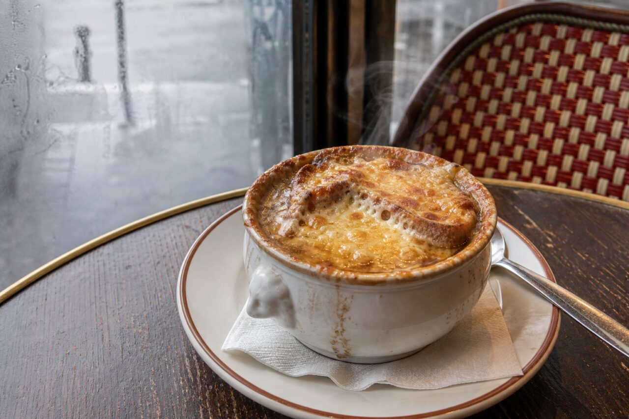 Sopa de cebolla gratinada en cuenco blanco con cuchara