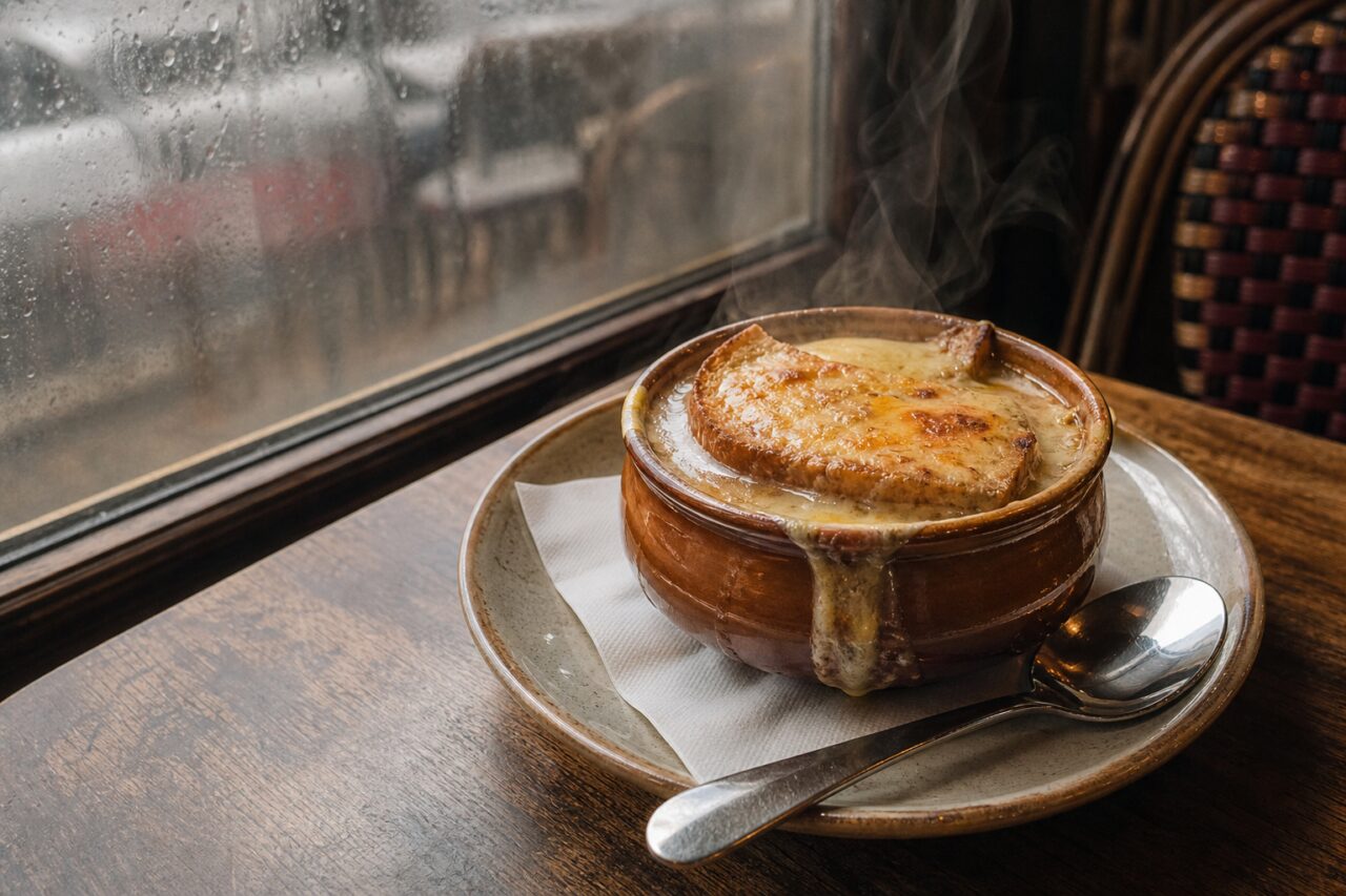 Überbackene Zwiebelsuppe im Tontopf auf einem Brasserie-Tisch