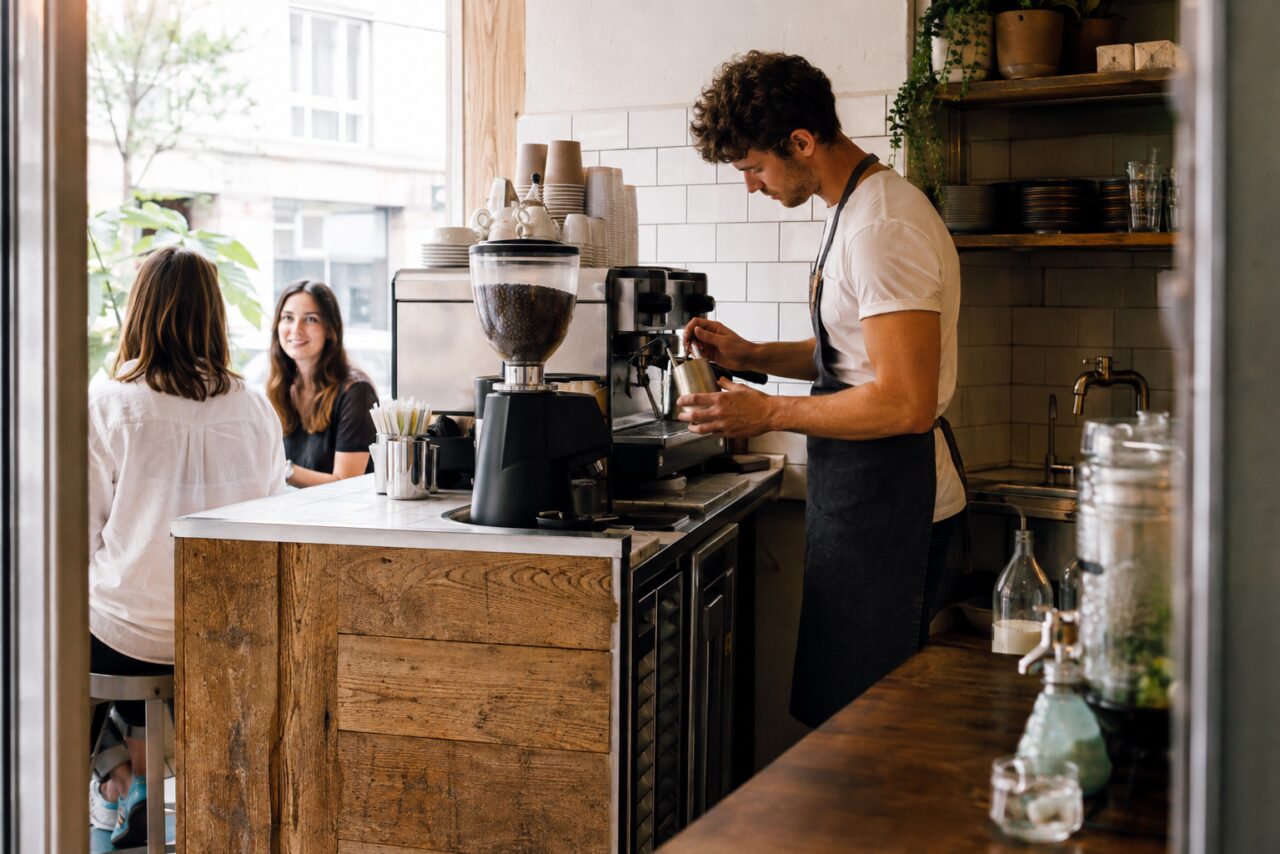 Innenraum eines unabhängigen Viertelcafés mit Barista, Kundinnen und Regalen