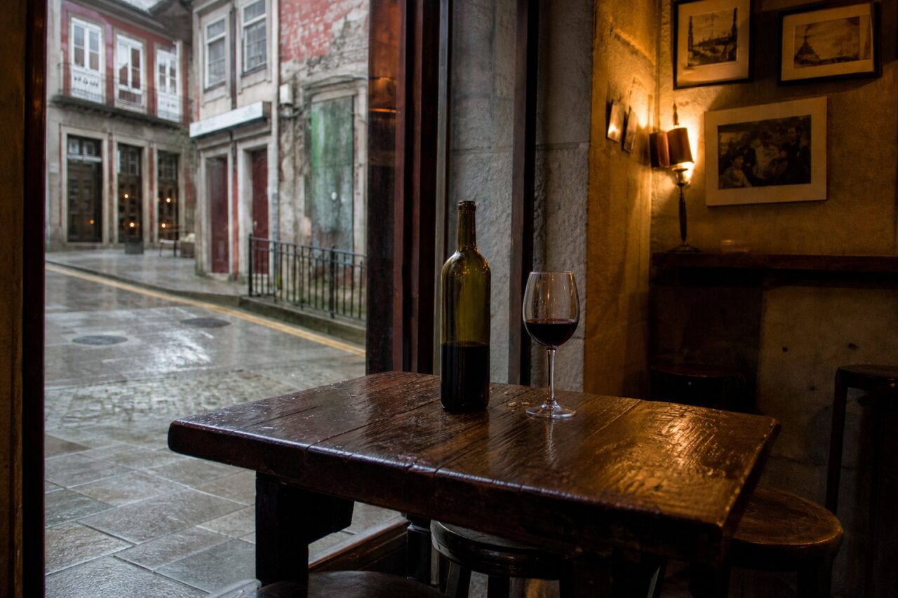 Full table by a wet street with bottle and glass centred