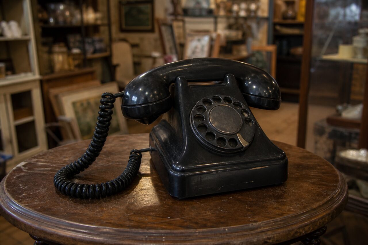 Telefono nero in bachelite con disco su un tavolo rotondo del negozio di antiquariato