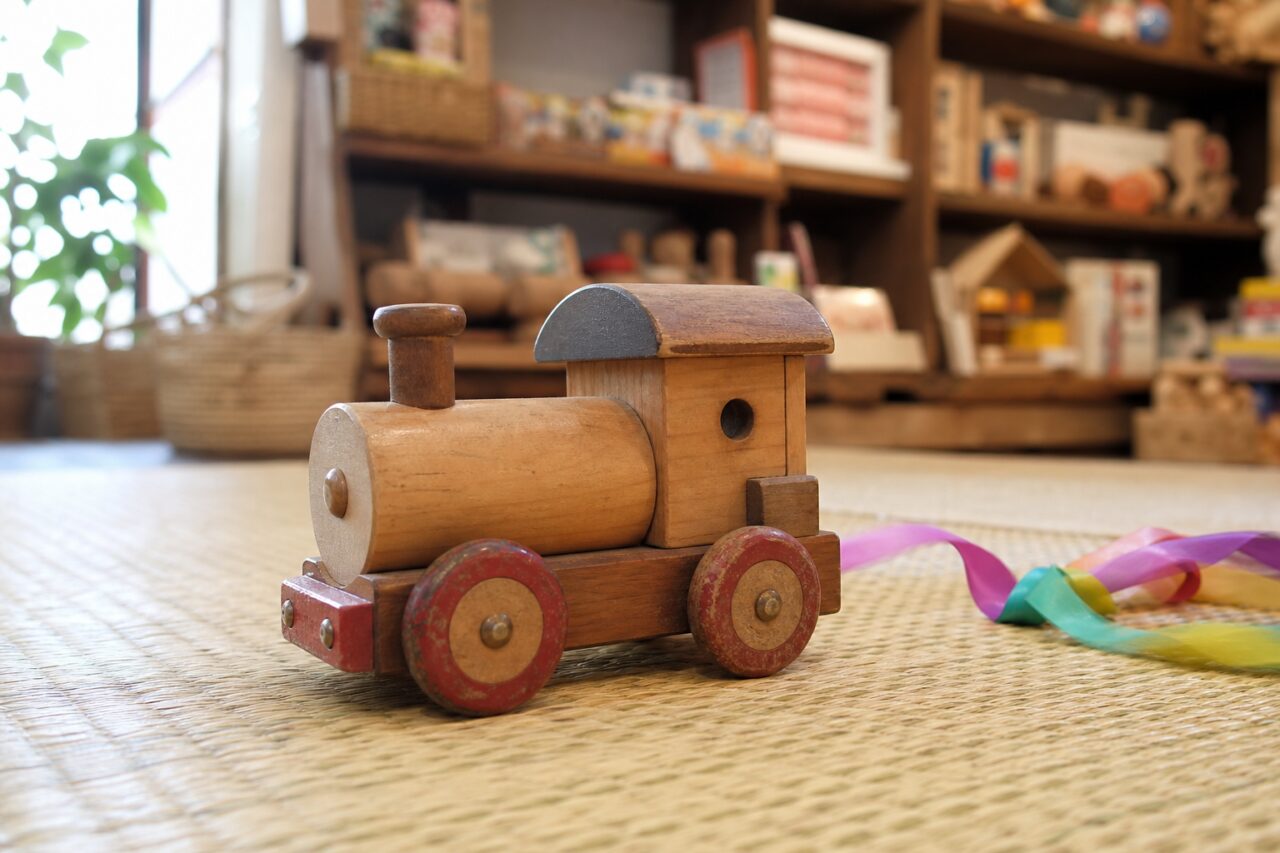 Tren de juguete de madera con ruedas rojas sobre una estera
