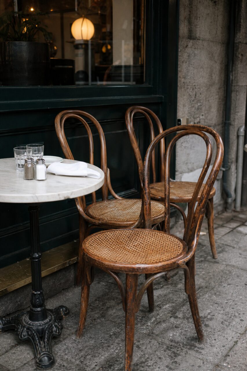 Three woven chairs around a round table by a window