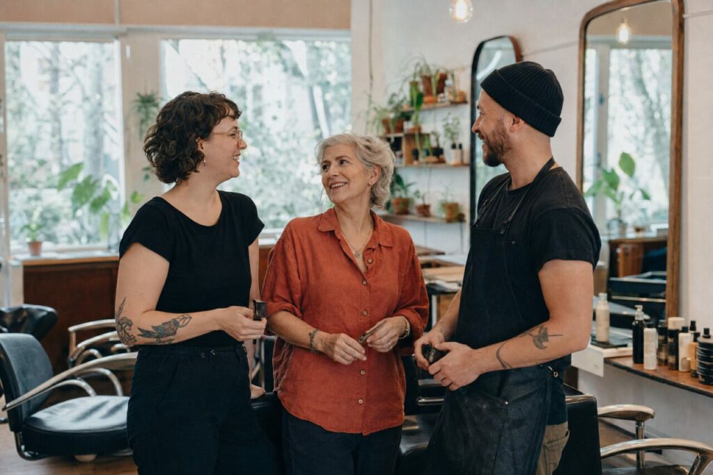 Trois personnes sourient entre les fauteuils du salon
