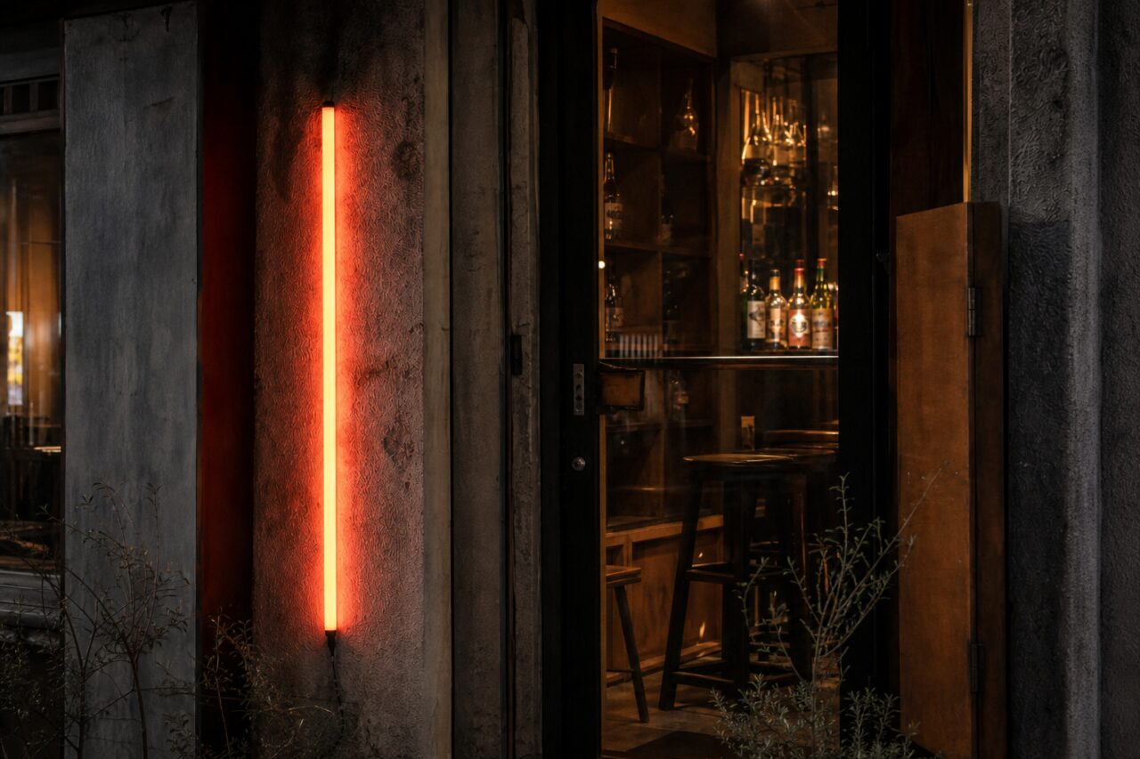 Oranje lichtbuis en flessen achter een glazen deur
