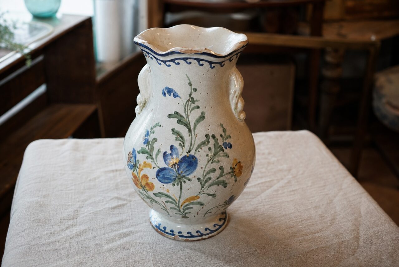 Jarrón de loza crema visto en ligero picado con abertura ondulada y decoración floral pintada