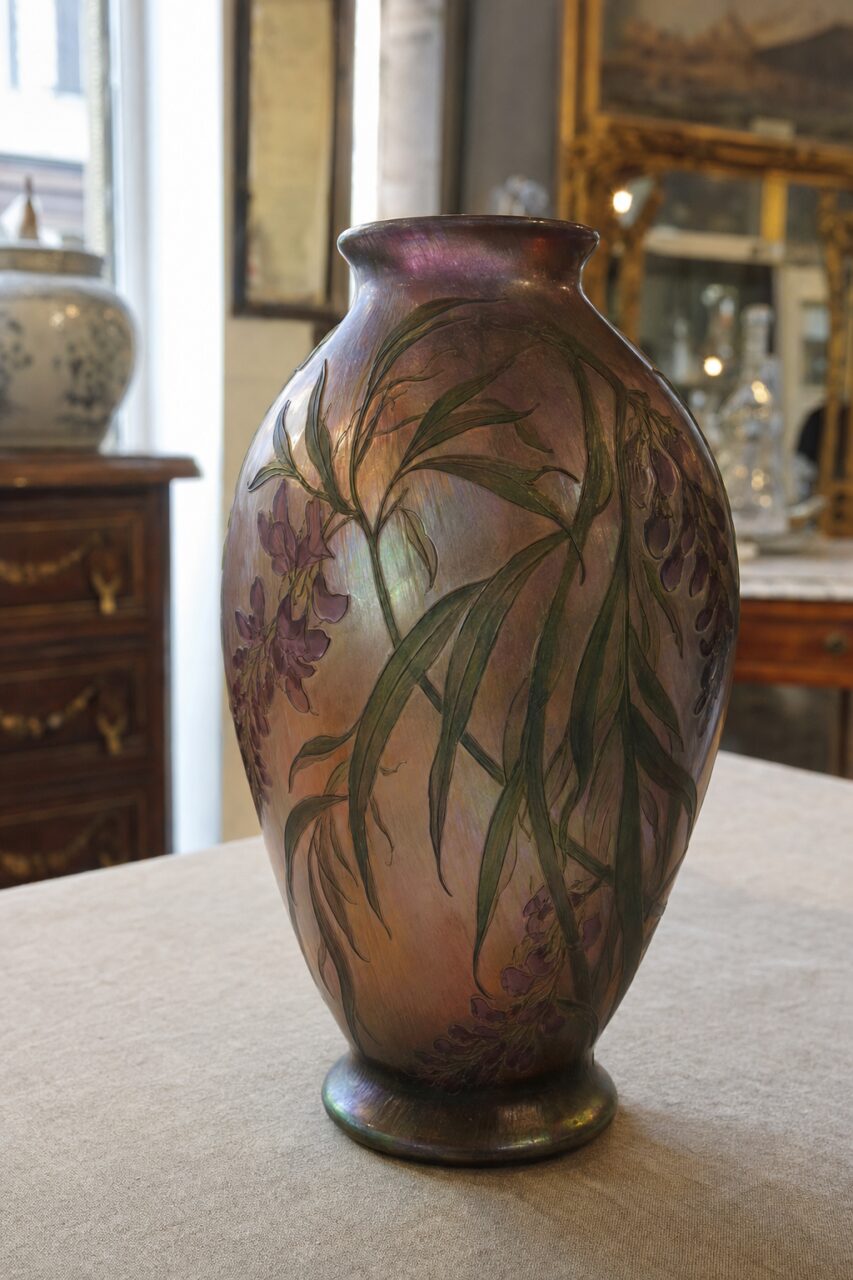 Ovoid iridescent vase with long green leaves and mauve flowers