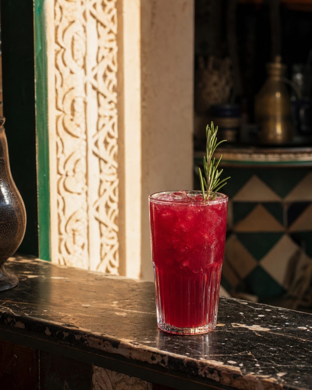 Vaso con líquido rojo ante un panel tallado