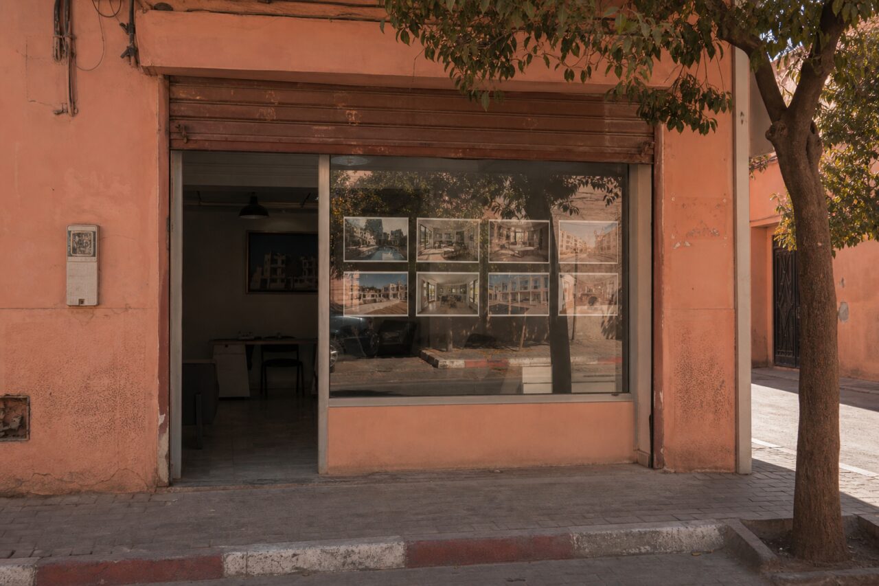 Agency window with property photographs beneath a tree
