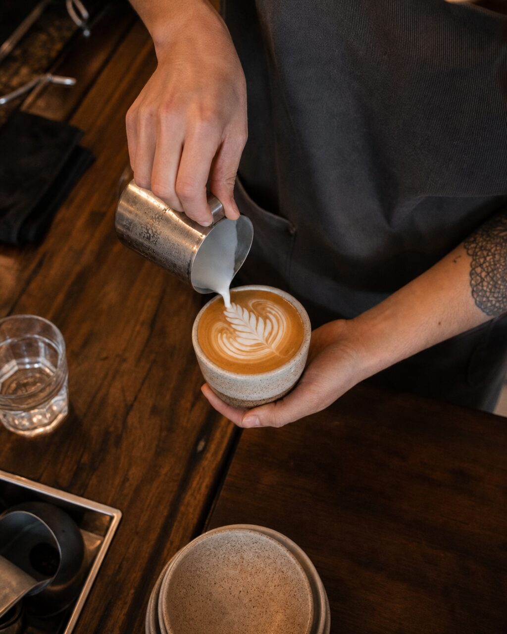 Bovenaanzicht van een persoon die melk in een koffiekop schenkt