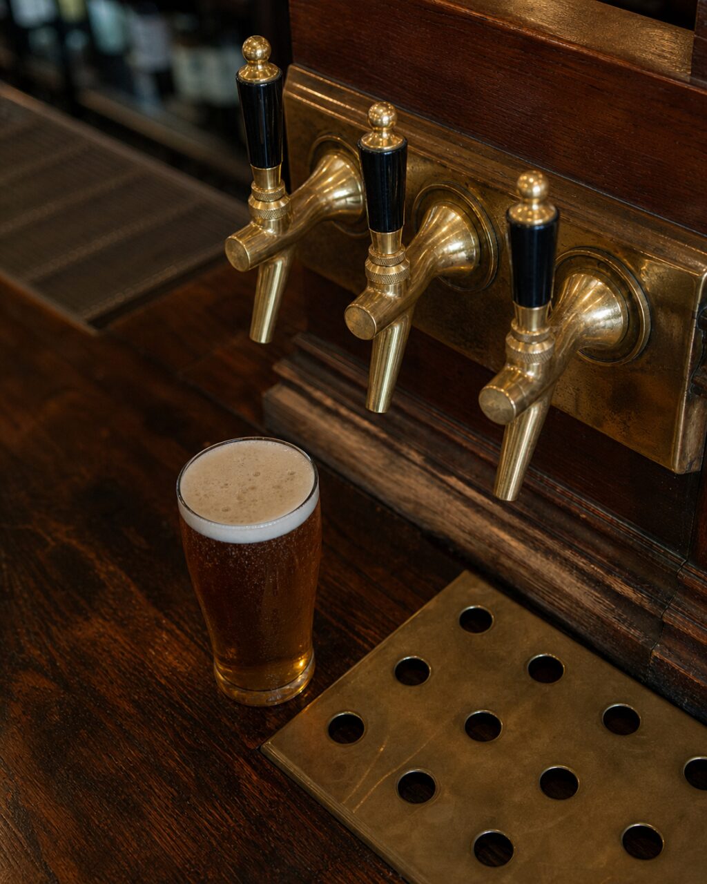 Bovenaanzicht van drie koperen taps en een glas bier