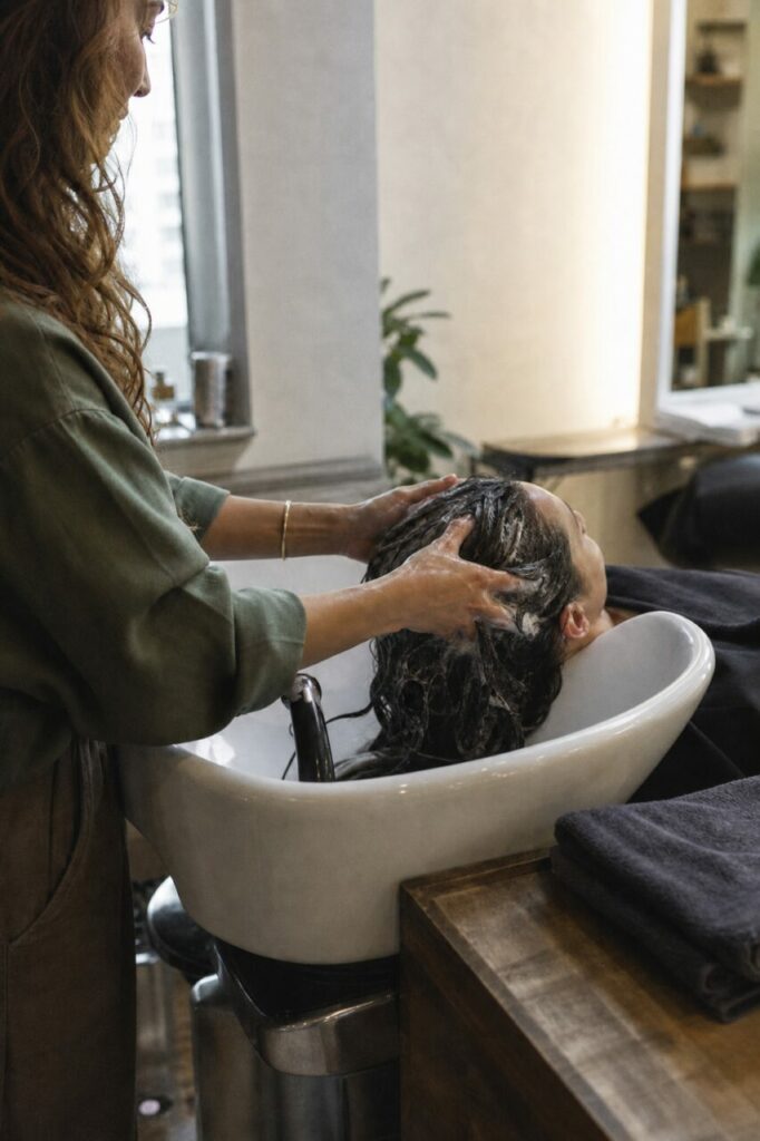 Weißes Haarwaschbecken mit glänzendem Ringfuß und dunklen Handtüchern