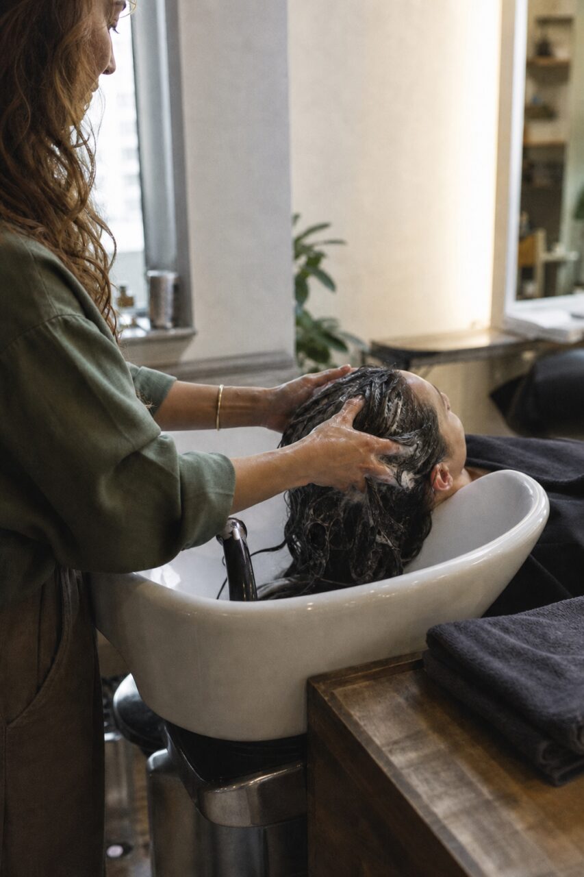 Weißes Haarwaschbecken mit glänzendem Ringfuß und dunklen Handtüchern